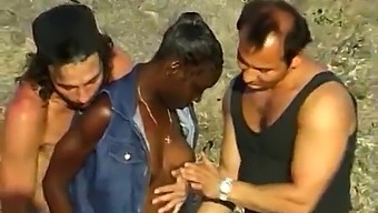 אישה אפריקאית נהנית משלישייה עם שני גברים לבנים בחוף הים